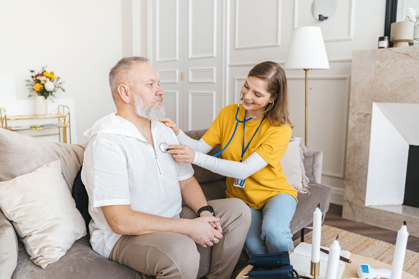 A caregiver checking on a senior man in a bright living room