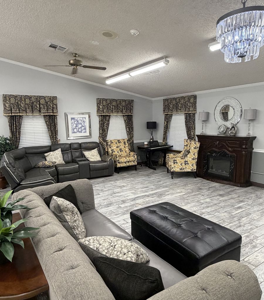 A bright living room with sofas, armchairs, a fireplace and a chandelier