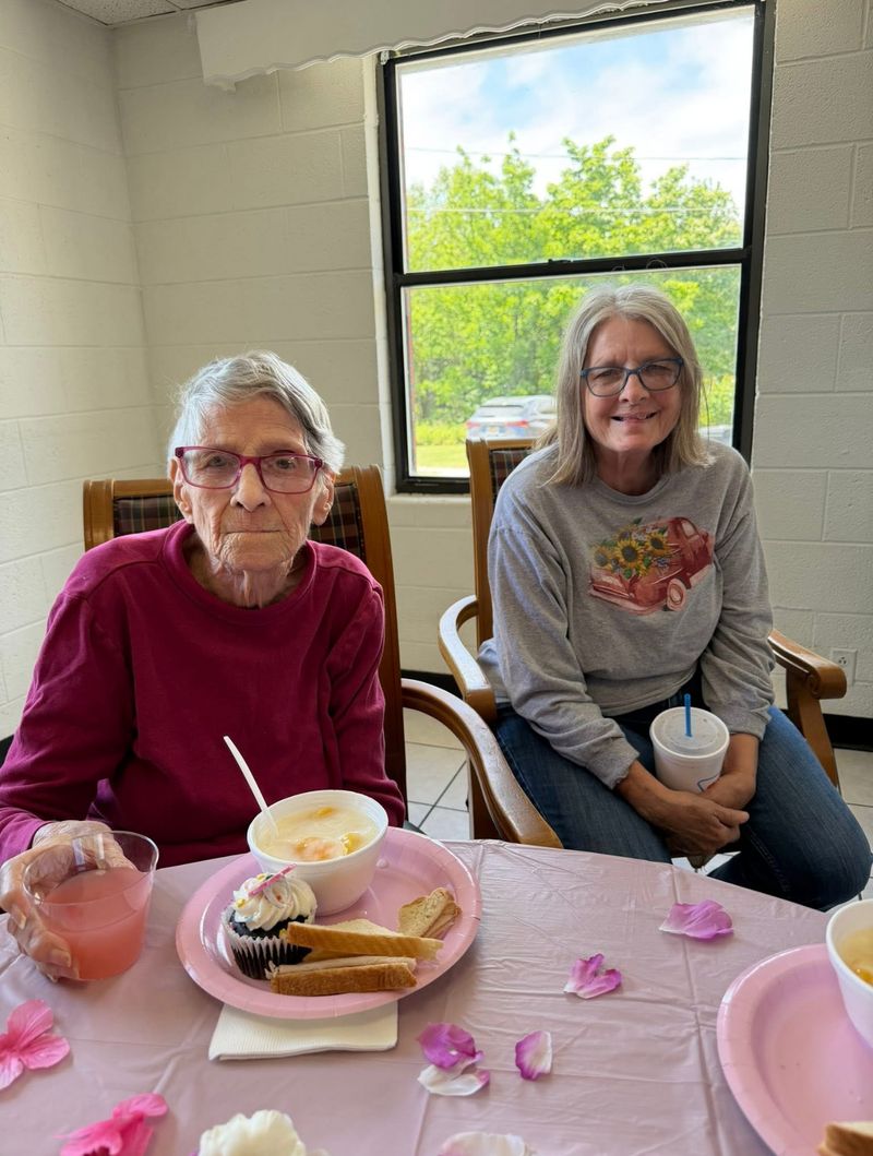 A smiling resident and a friend sharing a meal at a decorated table